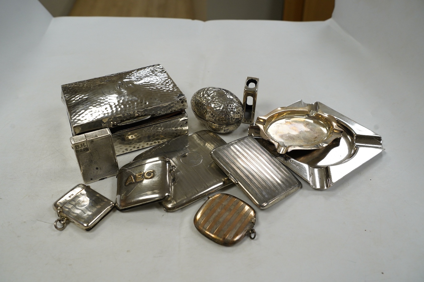 Eleven smoking related items including four silver vesta cases, one egg shaped, two silver ashtrays, two silver cigarette cases, a cigarette box, silver match sleeve and a silver plated Dunhill lighter. Condition - poor